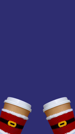 banner two christmas paper beige cups with white lid dressed in santa claus clothes on blue violet background, copy space, vertical, 16:9の写真素材