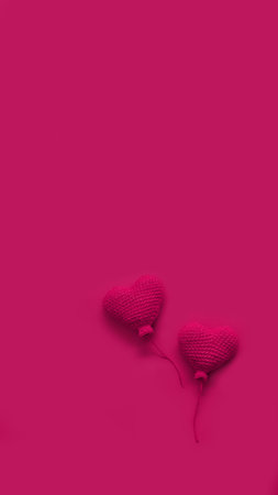 two red handmade knitted heart shaped balls on pink background, copy space, vertical, 16:9の写真素材