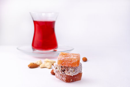 Oriental sweetness Turkish Delight on white background with glass of tea and nuts, copy space, selective focusの写真素材