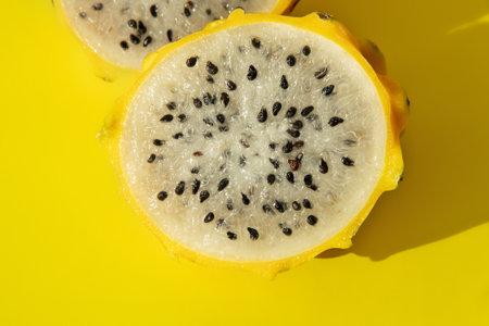 yellow pitaya dragon fruit in section white flesh with black seeds on yellow backgroundの写真素材