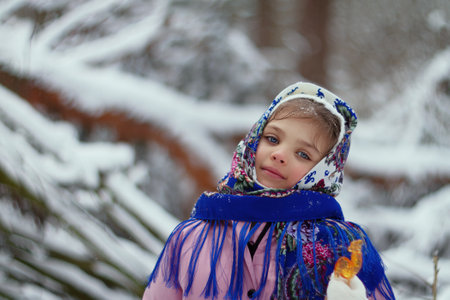 portrait girl 6 years old in pink winter clothes and national Russian blue scarf, in hands of sweet...
