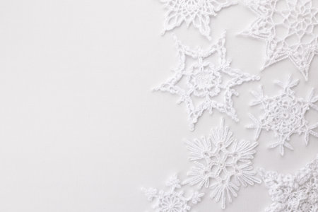 crocheted white lace snowflakes on white backgroundの写真素材