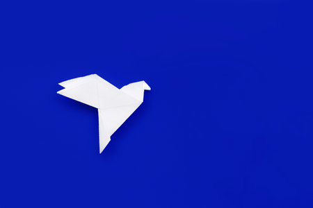 white paper origami pigeon on deep blue backgroundの写真素材