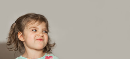 banner portrait of cheerful funny girl with cranky face looking to right on gray backgroundの写真素材