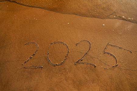 New year handwritten arabic numerals 2025 on wet yellow sand, calendar date