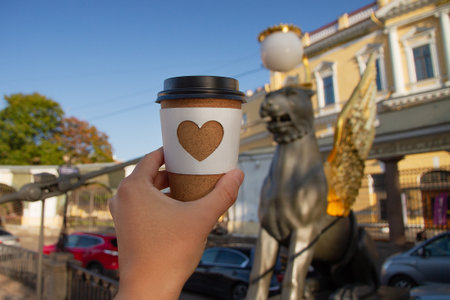 cup of coffee with heart design held up against the Bank Bridge in St. Petersburgの写真素材
