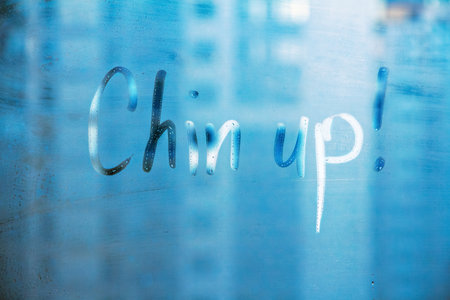 Hand drawn message Chin up on foggy glass on blue windowの写真素材