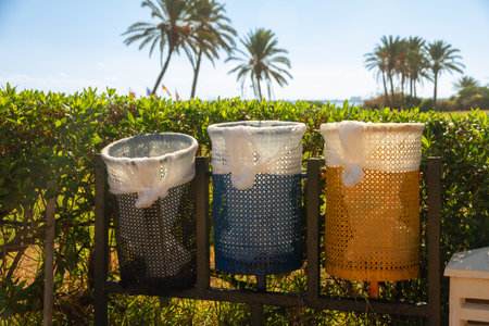 Three colorful mesh trash cans in tropical parkの写真素材