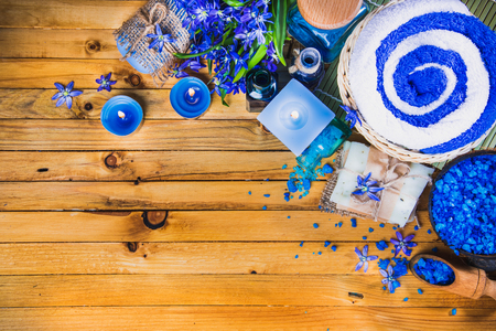 Spa concept in blue tones on a wooden surface: candle, sea salt, flowers, soaps, essential oils. Top view.の写真素材