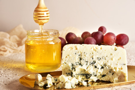 Fresh blue cheese on a golden saucer, honey and grapes.の写真素材