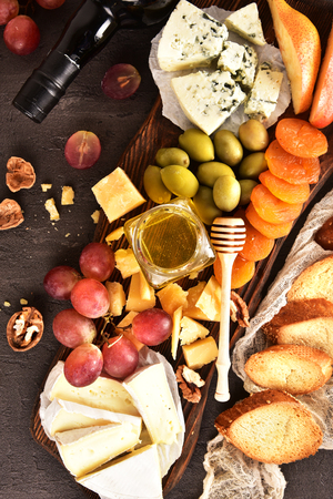 Set on a beige background. Different types of cheeses: Camembert, Parmesan, blue cheese, olives, honey, grapes.の写真素材