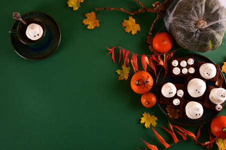 Halloween-themed concept: sugar ghosts, pumpkins, coffee on a dark green background. Place for your text.の写真素材