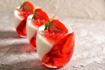 Two-color jelly of strawberries and cream in a beautiful glass, in a spring composition.の写真素材