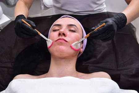 The beautician performs a facial cleansing procedure. Facial care, mask, scrub. Hardware facial cleansing. Skin rejuvenation and beauty.の写真素材