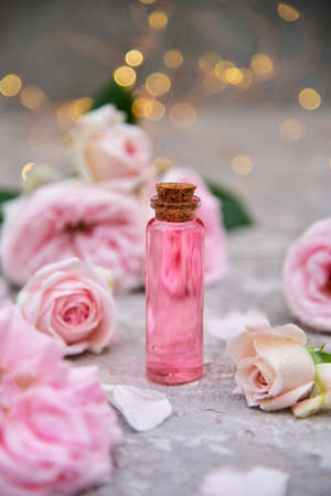 a bottle of rose oil on a background of rose flowers and bokehの写真素材