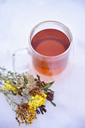 Tea from the collection of medicinal herbs on a background of snow. Healthy food, winter tea for colds.の写真素材