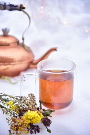 Tea from the collection of medicinal herbs on a background of snow. Healthy food, winter tea for colds.の写真素材