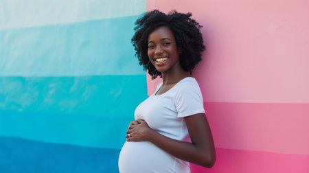 True mother love. African-american pregnant woman hugging her belly and smiling to camera, pink background with free spaceの素材