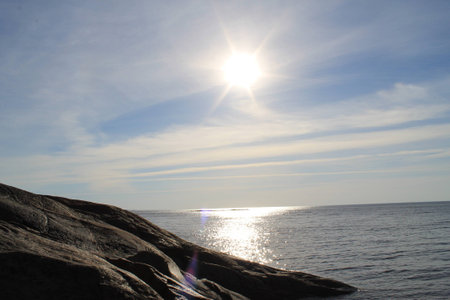 The bright sun illuminates the rocky coastの写真素材