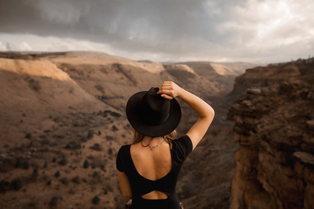 Young woman wearing hat standing by the mountainの写真素材