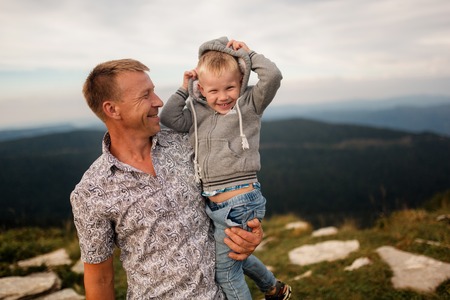 Father holds son on a mountain top at the summer