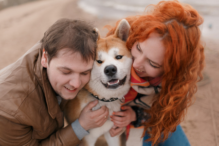 Young beautiful couple hugging an Akita dogの写真素材