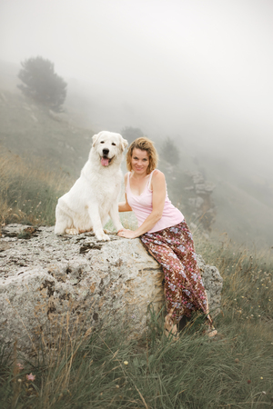 beautiful women and two white dogs morema sit on rock in fogの写真素材