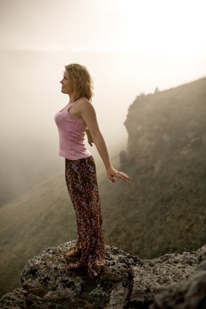 cool women stay on rock in mountain in canyon in fog smilingの写真素材