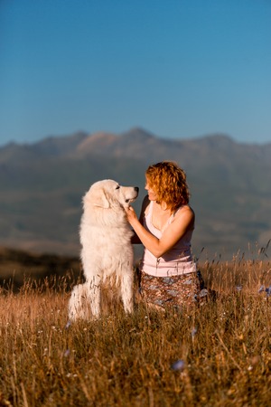 beautiful portrait women and cool white dog morema sit on grass in mountainの写真素材