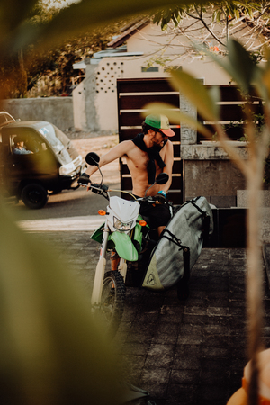 Portrait of beautiful smiling man on motorcycle in summer through the leaves of a palm tree