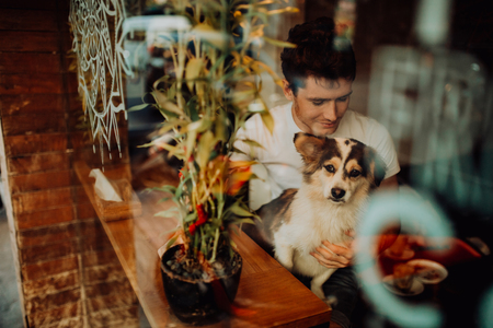 Businessman at coffee shop with dog. Best friends at cafe.の写真素材