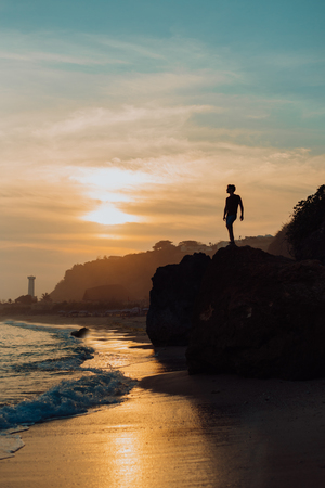 Strong fitness yoga man on the rock beach near the ocean. Harmonic concept, peace and success. silhouetteの写真素材