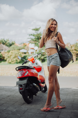 Sexy woman standing near the motobike. Lifestyle portrait bright toned colors,cool rock n roll girl,Enjoy ride in summer sunny hot daysの写真素材