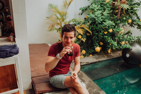 men eat crisps by swimming pool, man in swim pool with cocktailsの写真素材
