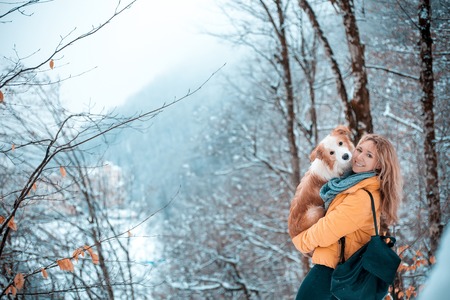 young stylish travel woman in mountain forest, looking forward, holding a dog, happy positive mood, winter, bohemian style outfit,の写真素材