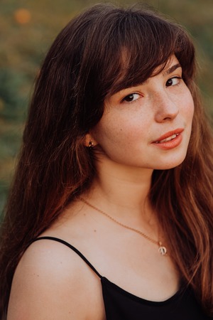 cute Trendy girl with hairstyle with red lips in black print dress on summer garden. mandarins. Redhead model in trendy summer dress in garden. Stylish hairstyleの写真素材