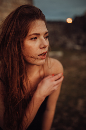 Portrait Trendy girl with hairstyle with red lips in black print dress on summer garden. mandarins. Redhead model in trendy summer dress in garden. Stylish hairstyleの写真素材
