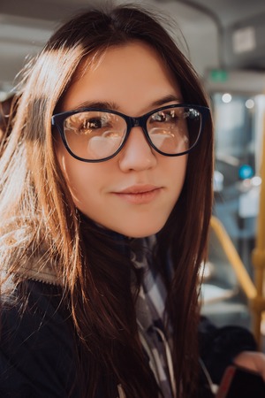 young Fashion cool girl hipster in glasses. bus town and city in background, not isolatedの写真素材