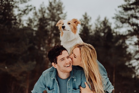 happy cheerful smiling man with girl and dog on his back. kissing couple of young people in denim...