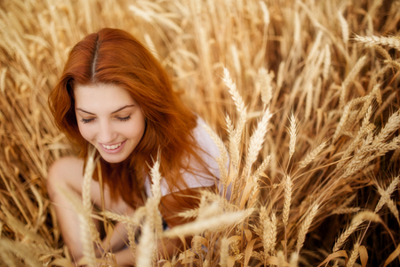 beautiful rockenroll red-haired girl stands in field in sunsetの写真素材