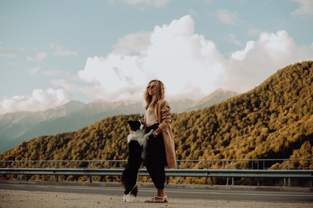 girl walking on the road with his dog in the mountainsの写真素材