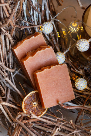 Handmade brown aromatic soap with cinnamon, dried fruits lies cosily on wood with lights. aroma postcard, close-up, verticalの写真素材