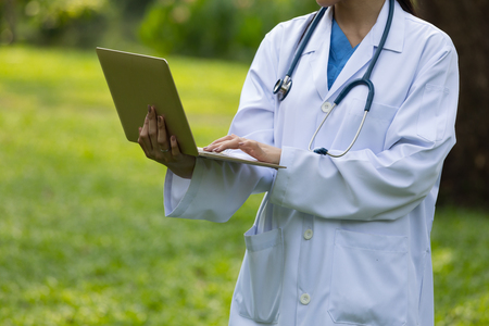 Doctor in white uniform with stethoscope and laptop the hospital's gardenの写真素材
