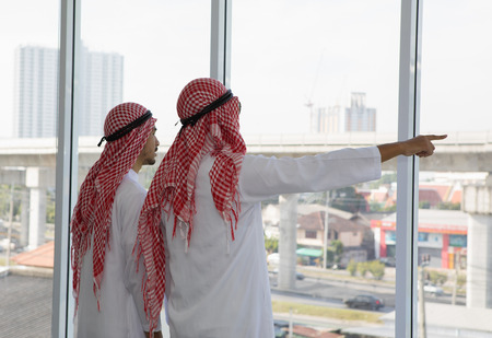 Two Arabian businessman pointing to big project buildingの写真素材