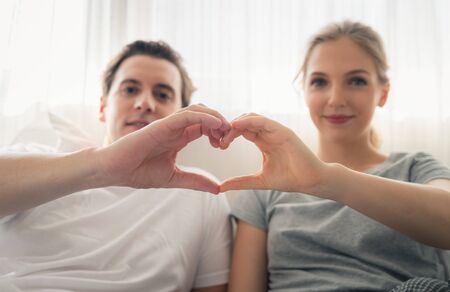 Couple young in love making heart shape with hands in bedroom.Celebrating Valentine's Dayの写真素材