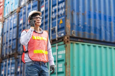 Foreman using smartphone to call check shipping products in Cargo freight ship at Cargo container...