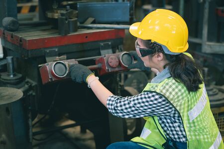 Female engineer wear safety vest and yellow helmet  working inspection machine equipment in line...