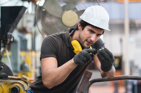 Male engineer adjusting part of machine equipment in line production at a factory industrial