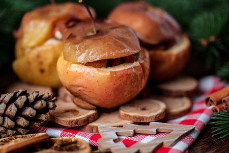 Baked apples with cinnamon on rustic background. Autumn or winter dessert. Closeup photo of a tasty baked apples with christmas decorationの写真素材