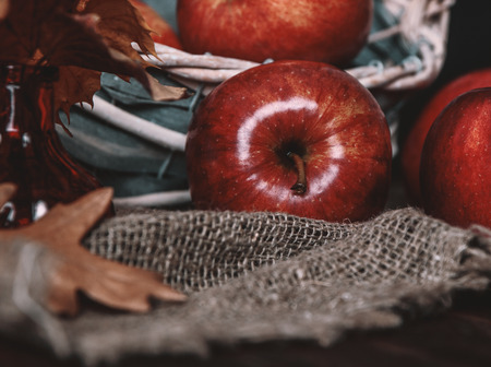 Autumn composition with fresh red apples in a wooden basket on rustic wooden background. Red apples on linen backgroundの写真素材